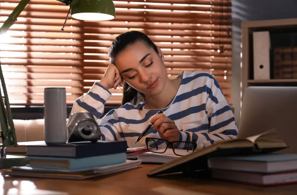 Tired young woman with energy drink studying at home