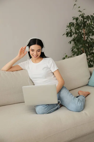 Frau Mit Laptop Und Kopfhörer Sitzt Hause Auf Sofa — Stockfoto