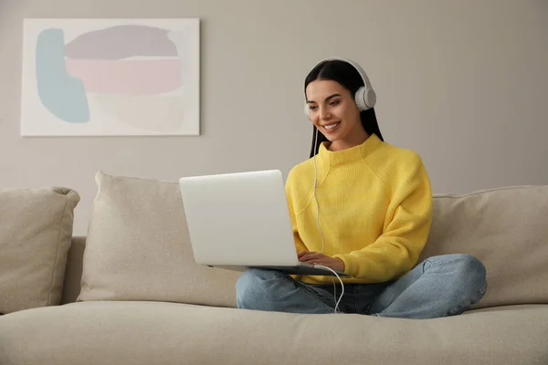 Γυναίκα Φορητό Υπολογιστή Και Ακουστικά Κάθεται Στον Καναπέ Στο Σπίτι — Φωτογραφία Αρχείου
