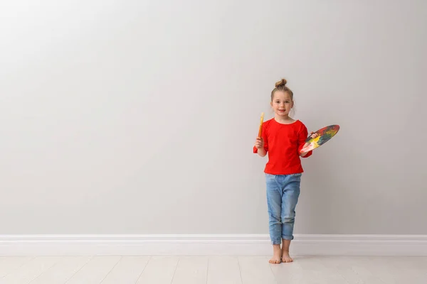 薄い灰色の壁の近くにブラシと塗料パレットを持つ小さな女の子が屋内 テキストのスペース — ストック写真