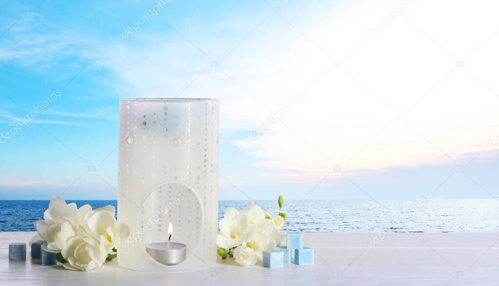 Composition with aroma lamp on white wooden table near sea , space for text. Banner design