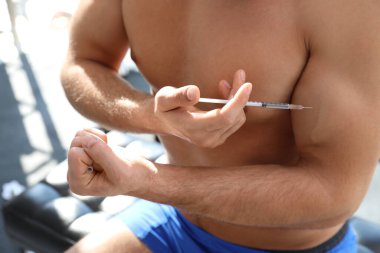 Atletik adam kendine kapalı alanda iğne yapıyor, yakın plan. Doping kavramı