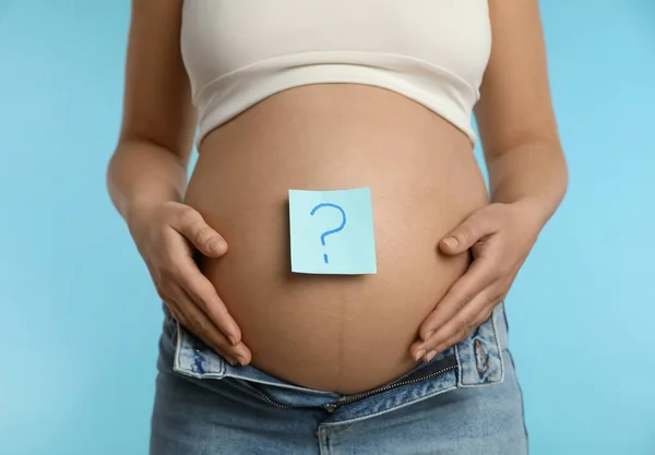 Zwangere Vrouw Met Plakkerig Briefje Buik Tegen Lichtblauwe Achtergrond Close — Stockfoto