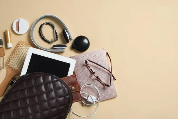 Stylish urban backpack with different items on beige background, flat lay. Space for text