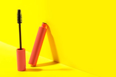 Sarı arka planda Mascara, mesaj için boşluk. Makyaj ürünü
