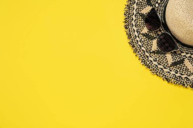 Sarı arka planda hasır şapka ve güneş gözlüğü, metin için yeri olan düz bir yer. Güneş koruması