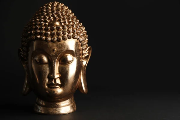 Beautiful golden Buddha sculpture on black background. Space for text