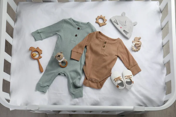 Płaska Kompozycja Cute Baby Ubrania Akcesoria Białym Prześcieradle Łóżeczku — Zdjęcie stockowe