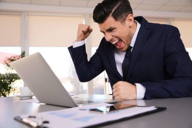 Ofisinde dizüstü bilgisayarı olan duygusal bir iş adamı.