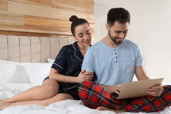 Glückliches Paar Schlafanzug Mit Laptop Auf Dem Heimischen Bett — Stockfoto