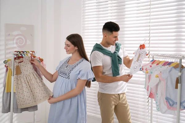 Gelukkige Zwangere Vrouw Met Haar Man Die Babykleertjes Petto Heeft — Stockfoto