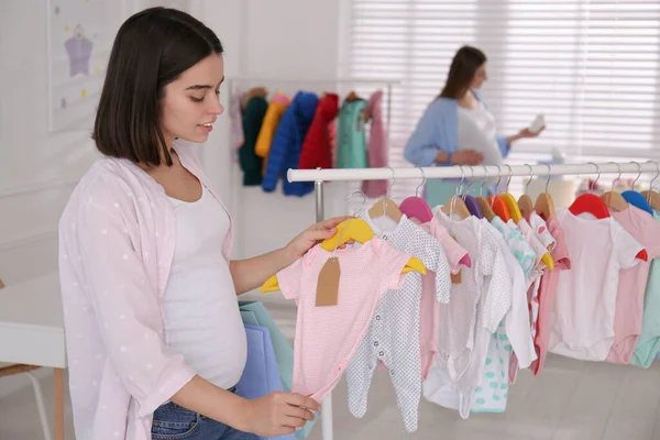 Alışveriş Torbalarıyla Mutlu Hamile Bir Kadın Mağazadan Bebek Kıyafetleri Seçiyor — Stok fotoğraf