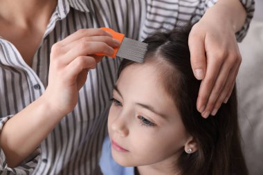 Anne, içeride kızının saçını bit tarağı ile tarıyor. Bit önleyici tedavi
