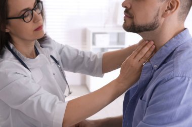 Hastanedeki hastanın tiroit bezini inceleyen doktor, yakın plan.