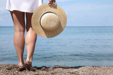 Sahilde suya yakın bir yerde hasır şapkalı bir kadın, yakın plan. Metin için boşluk