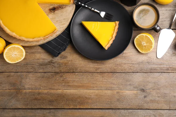 Delicious homemade lemon pie, fruits and coffee on wooden table, flat lay. Space for text