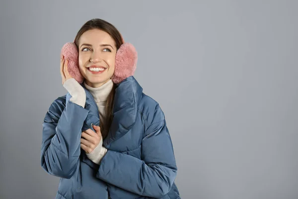 快乐的女人 戴着温暖的耳罩 灰色背景 文字的空间 — 图库照片