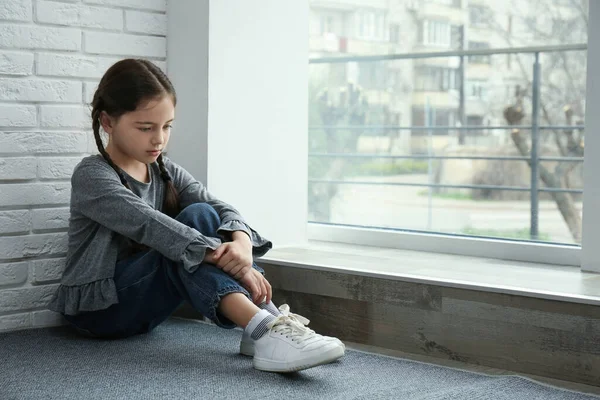 Trauriges Kleines Mädchen Sitzt Auf Dem Boden Neben Fenster Drinnen — Stockfoto