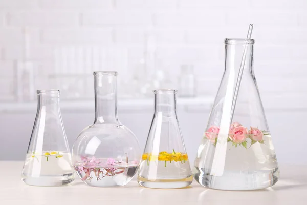 Vidrio Laboratorio Con Diferentes Flores Sobre Mesa Madera Blanca Extracción —  Fotos de Stock