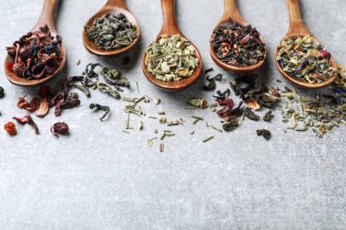 Açık gri taş masada farklı çay ve kaşıklarla kompozisyon. Metin için boşluk