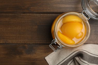 Cam kavanozdaki şeftali konserveleri ahşap masada, düz yerde. Metin için boşluk