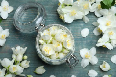 Mavi ahşap zemin üzerinde yasemin çiçekleri olan düz bir kompozisyon.