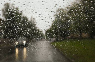 Islak arabanın penceresinden yolun bulanık görüntüsü. Yağmurlu hava