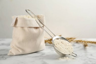 Beyaz mermer masa üzerinde un ile çuval ve elek