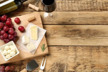 Düz kompozisyon, kırmızı şarap ve aperatifler ahşap masa üzerinde, metin için boşluk