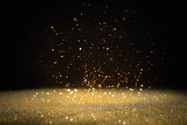 Siyah arkaplana dökülen parlak altın parıltı. Bokeh etkisi