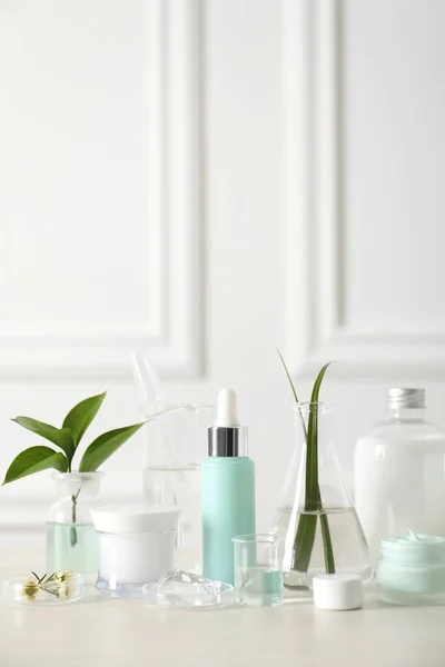 Natural ingredients for cosmetic products and laboratory glassware on white table