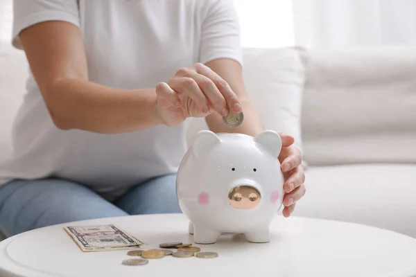 Woman Putting Coin Piggy Bank Table Indoors Closeup — Stock Photo, Image