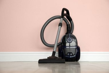 Pembe duvarın yanındaki modern elektrikli süpürge.