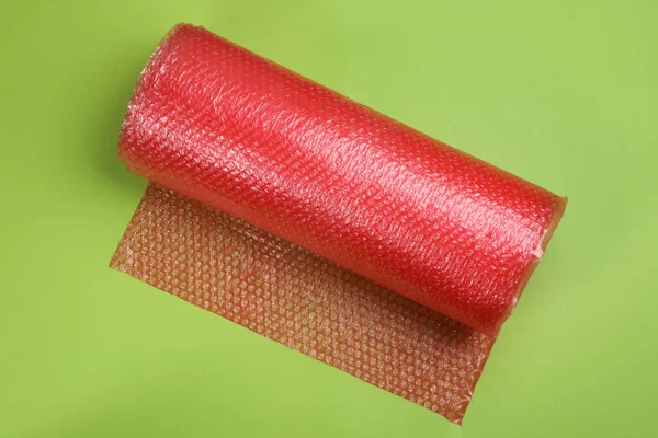 Bubble wrap roll on green background, top view