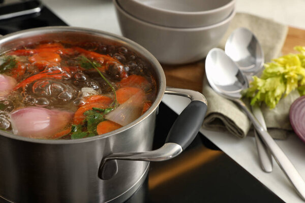 Pot of delicious vegetable bouillon on stove in kitchen, closeup
