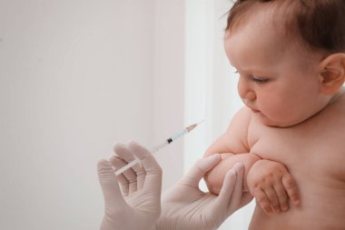 Doktor arka planda bebeğe aşı yapıyor. Sağlık hizmetleri