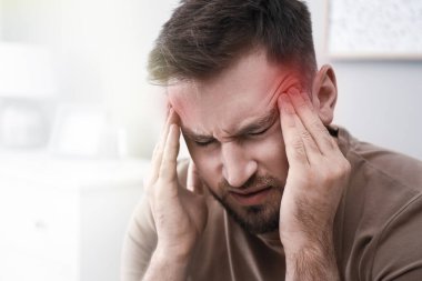 Young man suffering from migraine at home, closeup clipart