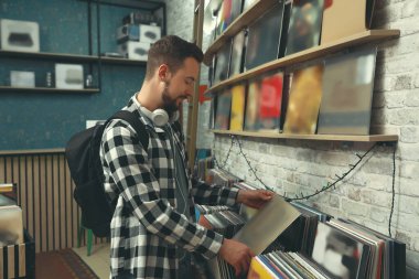 Delikanlı mağazada plak seçiyor.