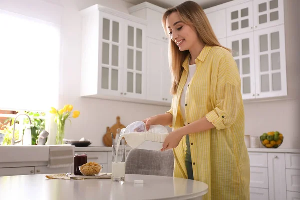 Mujer Joven Vertiendo Leche Botella Galón Vidrio Mesa Blanca Cocina — Foto de Stock