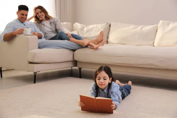 Little Girl Reading Book While Parents Sofa Home — Stock Photo, Image
