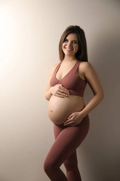 Беременная Молодая Женщина Трогает Живот Бежевом Фоне — стоковое фото
