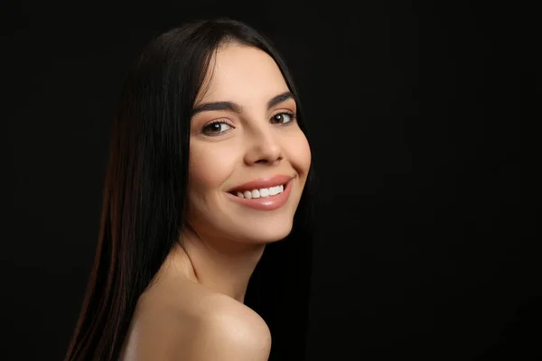 美しい黒い髪と暗い背景に魅力的な笑顔を持つ幸せな若い女性の肖像 テキストのためのスペース — ストック写真
