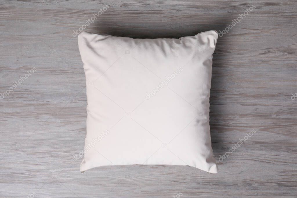 Blank soft pillow on wooden background, top view