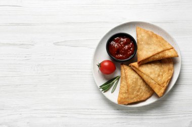 Beyaz ahşap masada servis edilen taze, lezzetli ve çıtır samosalar. Metin için boşluk