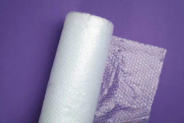 Bubble wrap roll on purple background, top view