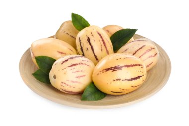 Taze olgun pepino kavunları ve beyaz arka planda yeşil yaprakları olan bir tabak.