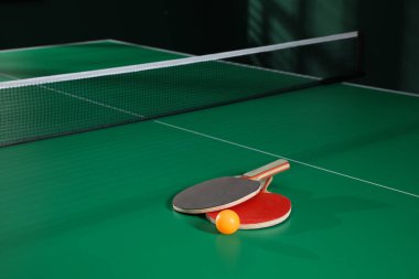 İçerideki yeşil masa tenisi masasında raketler ve toplar. Metin için boşluk