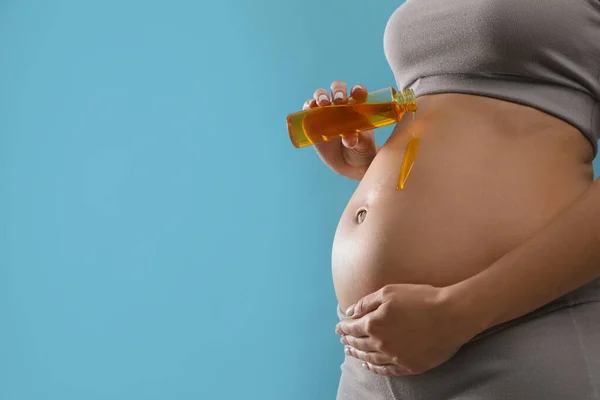 Mulher Grávida Aplicando Produto Cosmético Barriga Contra Fundo Azul Claro — Fotografia de Stock