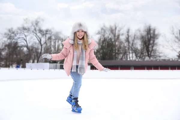 Happy woman skating along ice rink outdoors