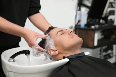 Profesyonel berber müşterinin saçını kuaförde yıkıyor.